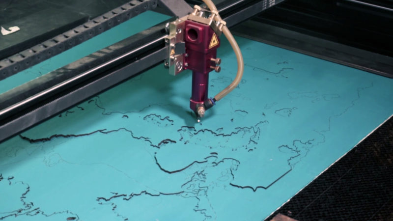 Een lasermachine snijdt een decoratieve landkaart uit.