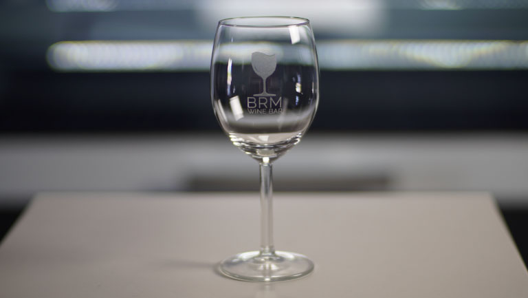 Een gegraveerd wijnglas met het logo van een wijnbar.